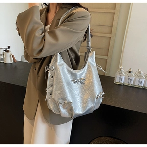 Detailed view of silver metallic underarm bag with bow knots and drawstring details