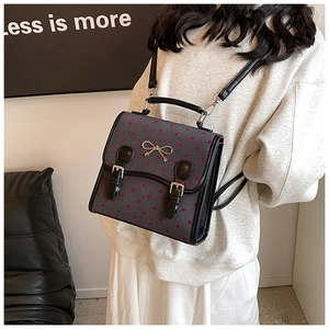 Detail of grey PU mini backpack with red heart patterns and metal bow on flap