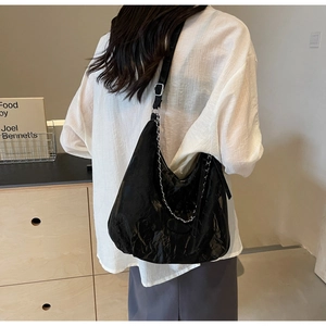 Detail of glossy black PU leather hobo bag with pleated texture and metal chain