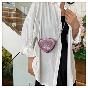 Detail of a mini heart-shaped crossbody bag with pink rhinestones and silver chain