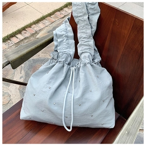 Borsa a spalla in nylon azzurro con borchie argentate e tracolla plissettata
