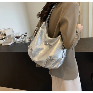 Close-up of silver PU leather crossbody bag featuring bows and wrinkled texture