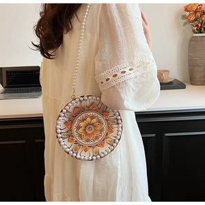Chic round woven crossbody bag with mandala pattern and elegant pearl shoulder strap