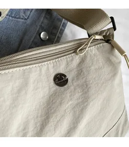 Detailed close-up of smooth beige fabric texture and durable zipper on crossbody bag