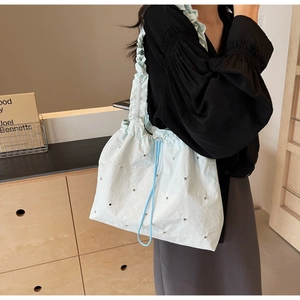 Detail of light blue crossbody bag with silver studs and ruffled shoulder strap