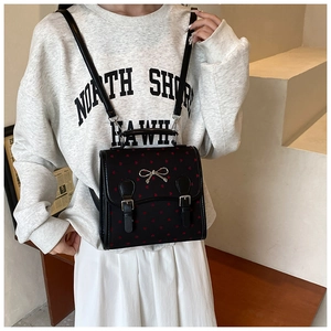 Detail of black backpack with red heart embroidery and silver metallic bow buckle