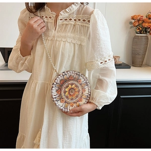 Detail of round boho linen crossbody bag with mandala pattern and pearl strap accents