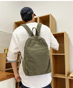 Detail view of army green canvas backpack showing back straps and ergonomic fit on model