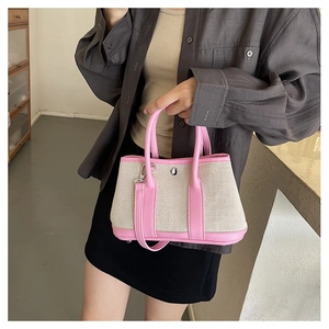 Detail of canvas tote bag with pink leather trim and detachable shoulder strap on model