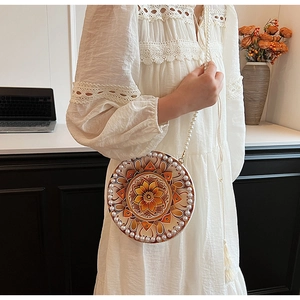 Close-up of a circular ethnic cotton linen crossbody bag with pearl strap and fringe