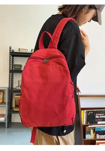 Side view of red canvas backpack on model showing large capacity and sturdy straps