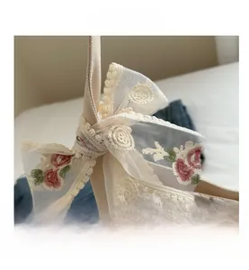 Close-up of elegant lace bow with floral embroidery on a beige canvas handbag