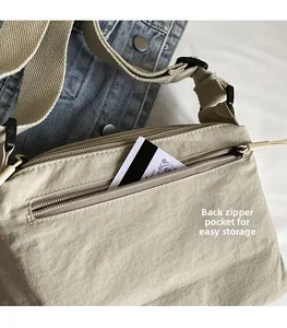 Detail view of functional back zipper pocket on a beige nylon crossbody bag with strap