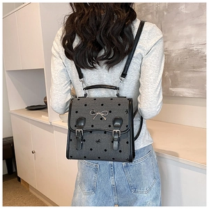 Polka dot vintage backpack with silver bow detail shown on a model in a bright room