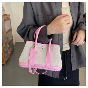 Detail of the pink leather handles and silver metal buckle on the canvas crossbody bag