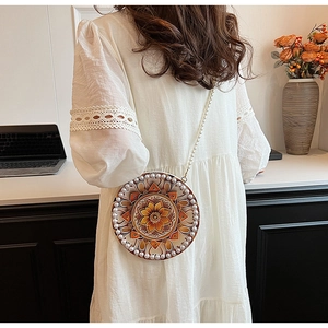 Macro detail of round mandala pattern crossbody bag with decorative white pearls trim