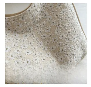 Detailed close-up of beige canvas handbag with delicate white floral embroidery patterns