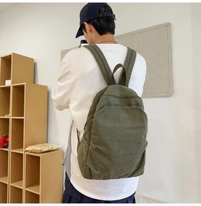 Rear view of model wearing army green canvas backpack with wide straps for daily use