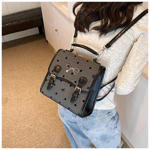 Polka dot gray backpack featuring silver bow hardware and black leather straps detail