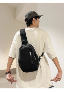 Detailed view of black canvas crossbody bag with silver zippers on a casual model outfit