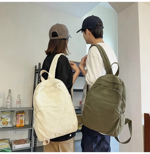 Detail view of cream and olive canvas backpacks worn by models in a minimalist lifestyle setting