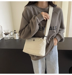 Close-up of adjustable fabric strap and zipper detail on cream crossbody bag