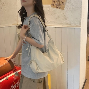 Detail of beige nylon crossbody bag featuring a stylish ruched scrunchie shoulder strap