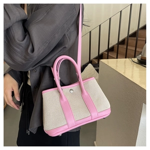 Detailed close-up of pink leather and beige canvas tote bag with adjustable shoulder strap
