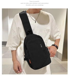 Detail of minimalist black canvas crossbody bag with orange tag and metal zippers