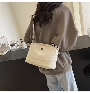 Detailed macro view of beige nylon crossbody bag texture with side drawstring detail