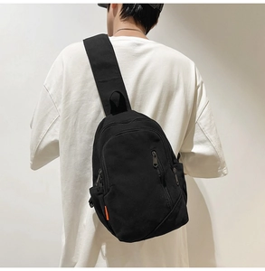 Detail view of a black canvas crossbody bag showing durable fabric and zipper pockets