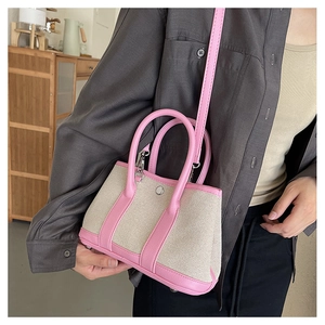 Detail view of small canvas handbag with pink faux leather trim and metal snap button closure