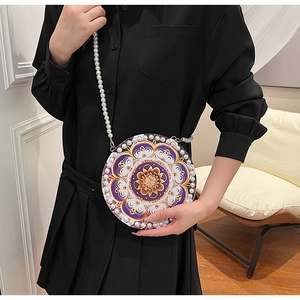 Detailed macro view of a round linen crossbody bag featuring purple mandala patterns and pearls