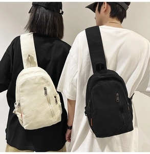 Detailed comparison of black and cream canvas crossbody bags worn by a fashion model