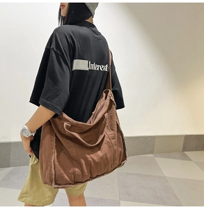 Detail view of brown canvas crossbody bag with frayed edge design and large capacity