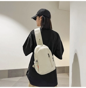 Modern off-white canvas crossbody bag styled on model in minimalist outdoor setting