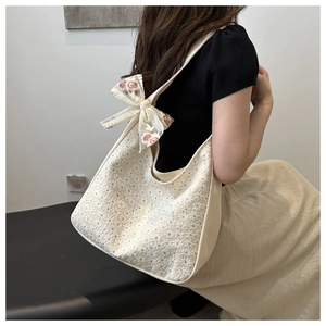 Detail of floral lace embroidery canvas bag with a large organza bow on shoulder strap