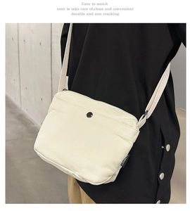 Close-up of beige canvas crossbody bag with metal buckle and detailed fabric texture