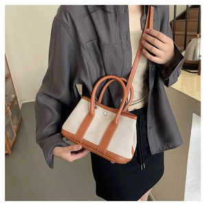 Chic canvas and brown leather crossbody bag styled on a person in a modern interior