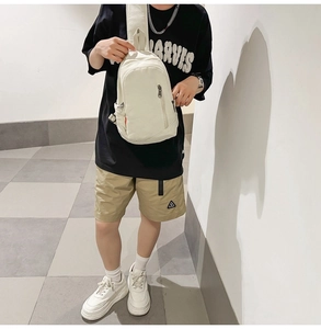Close-up of minimalist off-white canvas crossbody bag with multiple zipper pockets