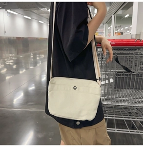 Detail of minimalist cream canvas crossbody bag with adjustable strap on a model