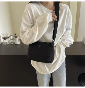 Street style shot of a black nylon crossbody bag paired with a white oversized sweatshirt