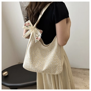 Detail of cream lace underarm bag with floral embroidery and a pink flower bow