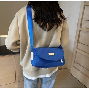 Detailansicht der kleinblauen Nylon-Umhängetasche mit Klappendesign und breitem Gurt