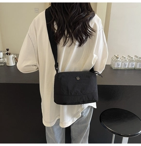 Detail of adjustable wide shoulder strap on a black minimalist fabric crossbody bag