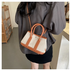 Detailed side view of two-tone PU leather tote bag worn by a model in warm setting