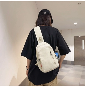 Detailed back view of a beige canvas crossbody bag with red label and zipper detail
