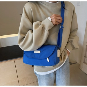 Detail der blauen Nylon-Umhängetasche mit verstellbarem Gurt und weißem Lederpatch