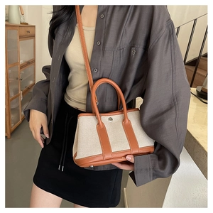 Detail view of canvas and brown leather crossbody bag with metallic snap button closure