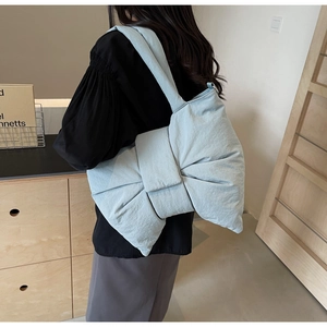 Detail of light blue oversized bow shoulder bag in soft padded fabric on model